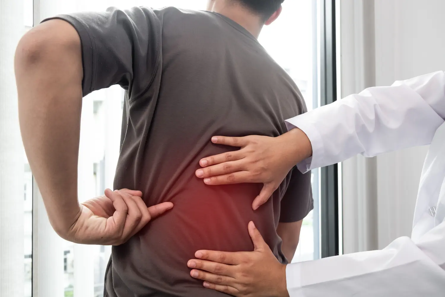 Agbalik Physiotherapie - Therapeutin behandelt verletzten Rücken eines männlichen Patienten.
