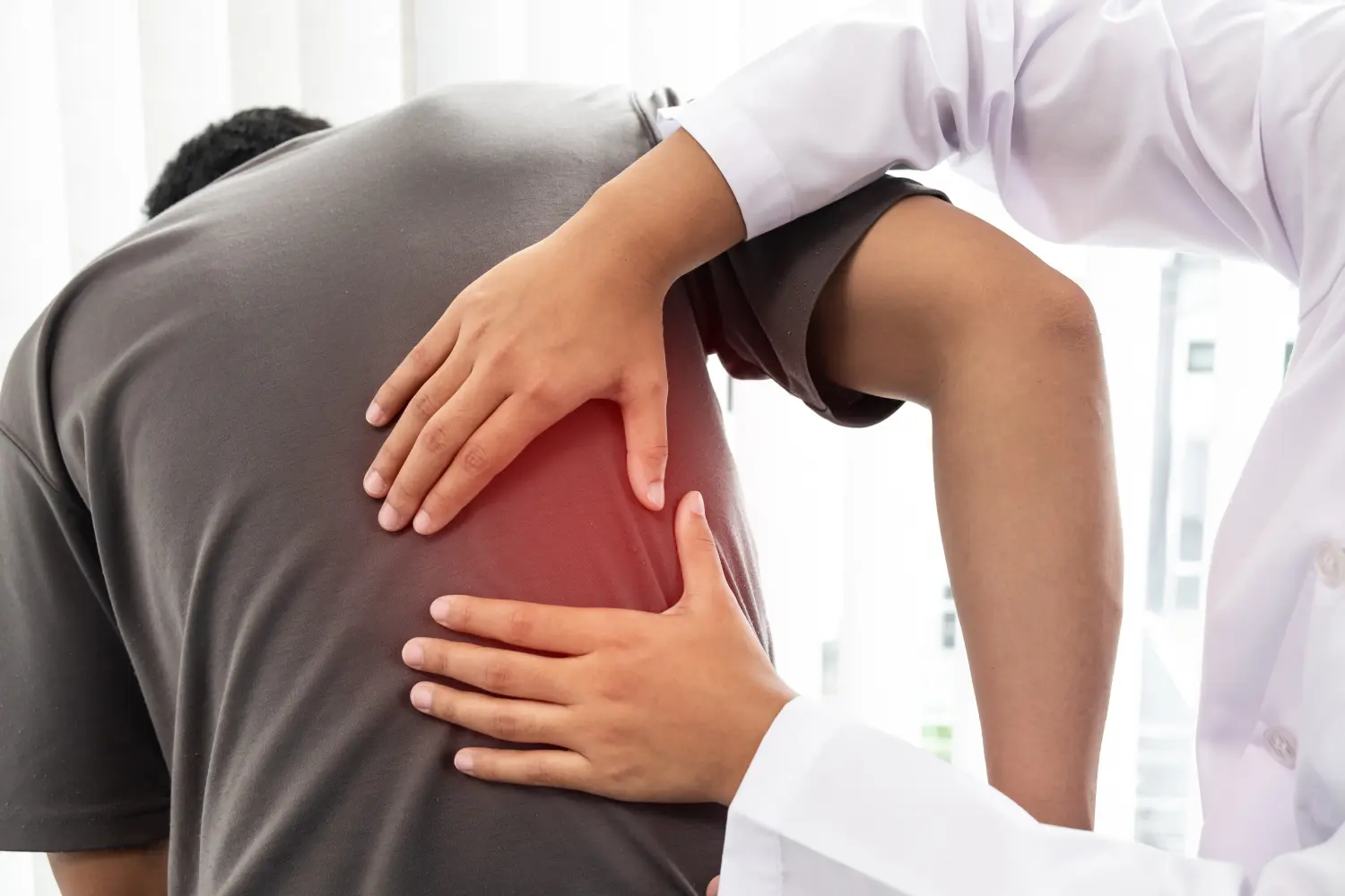 Agbalik Physiotherapie - Therapeutin behandelt verletzten Rücken eines männlichen Patienten.